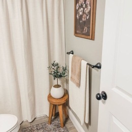 bathroom with toilet shower curtain towel rack and plant on a stool